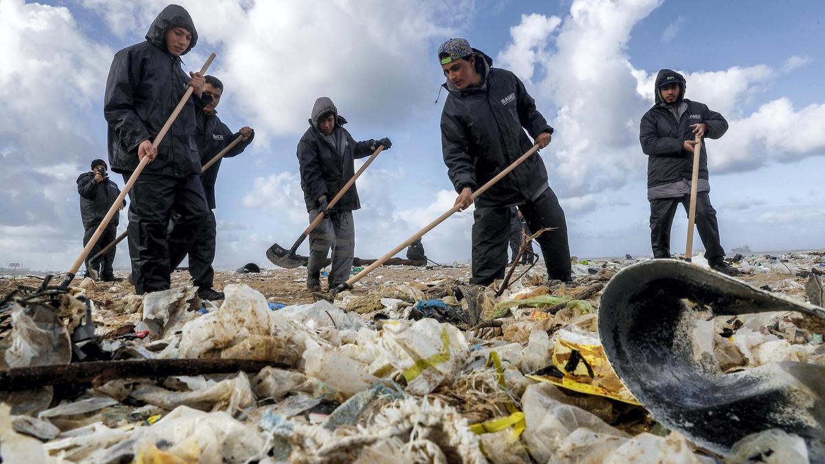 Workers clean the beach of the coastal town of Zouk Mosbeh, north of Beirut, on January 23, 2018. AFP